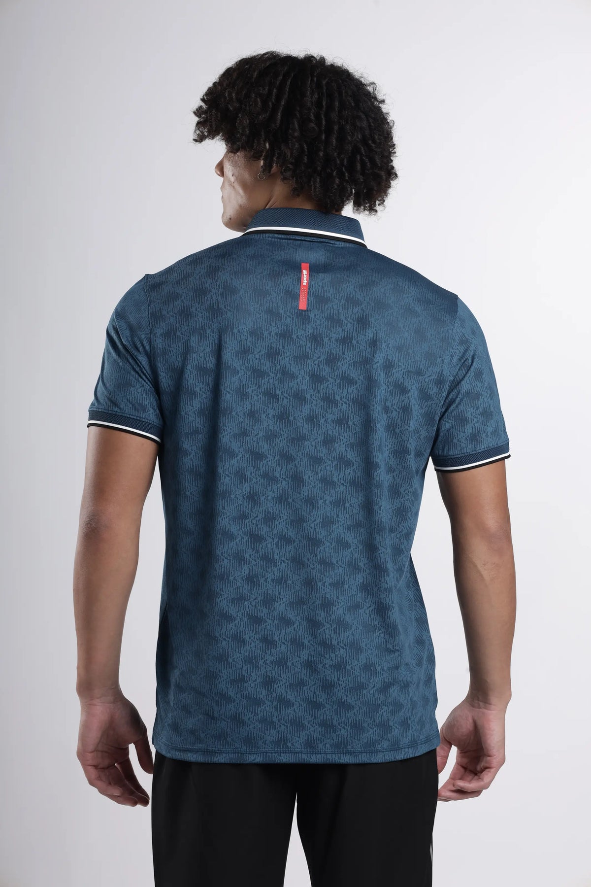 AeroEdge Performance Polo T-Shirt in dark teal, back view on a model showing the red tab below the collar