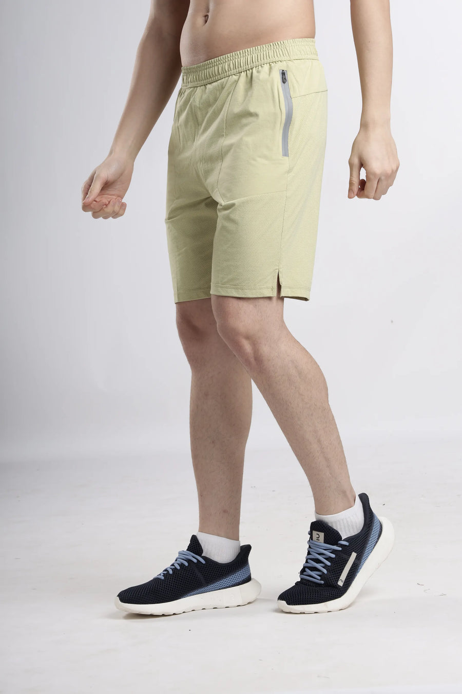 AirWave Performance Shorts in sand, side view on a model showing the zip pocket and slit hem