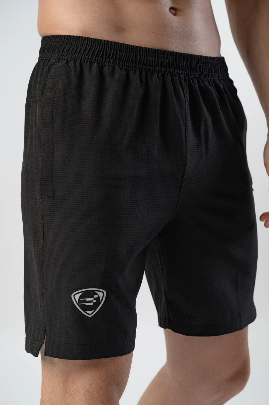 Fast-Track Running Shorts in black, close-up of the elastic waistband, shield logo and split hem