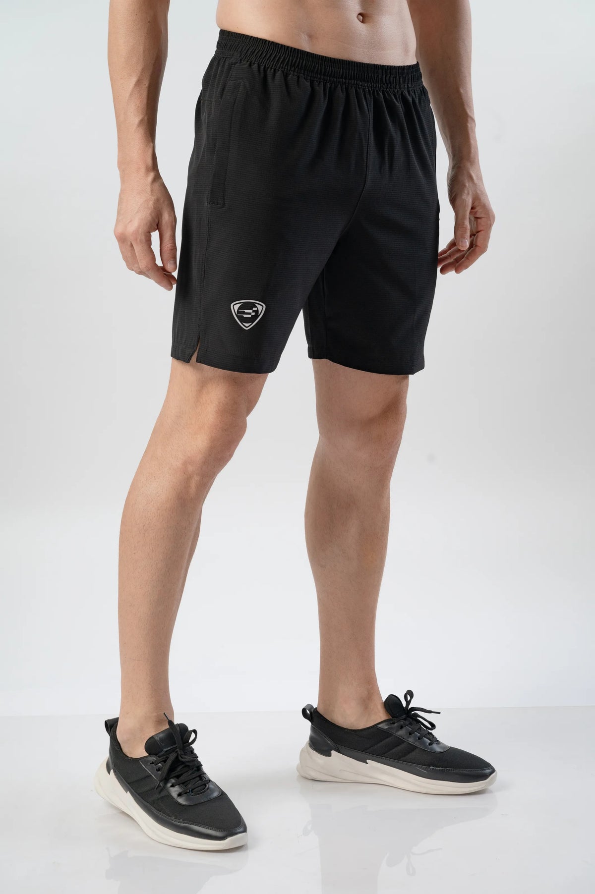Fast-Track Running Shorts in black, angled side view on a model showing the shield logo and split hem