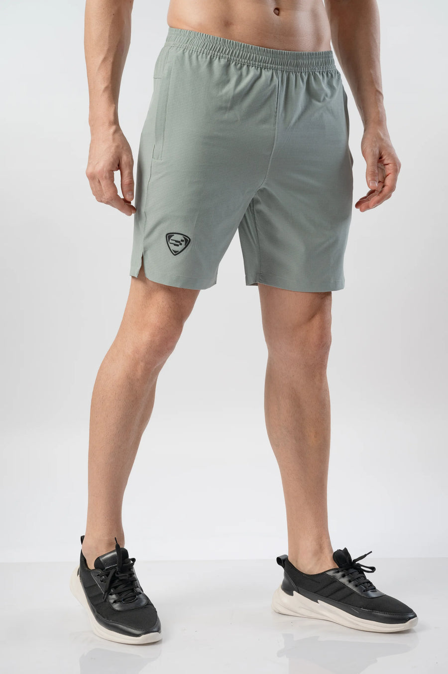 Fast-Track Running Shorts in super sage, angled front view showing the shield logo and side slit hem