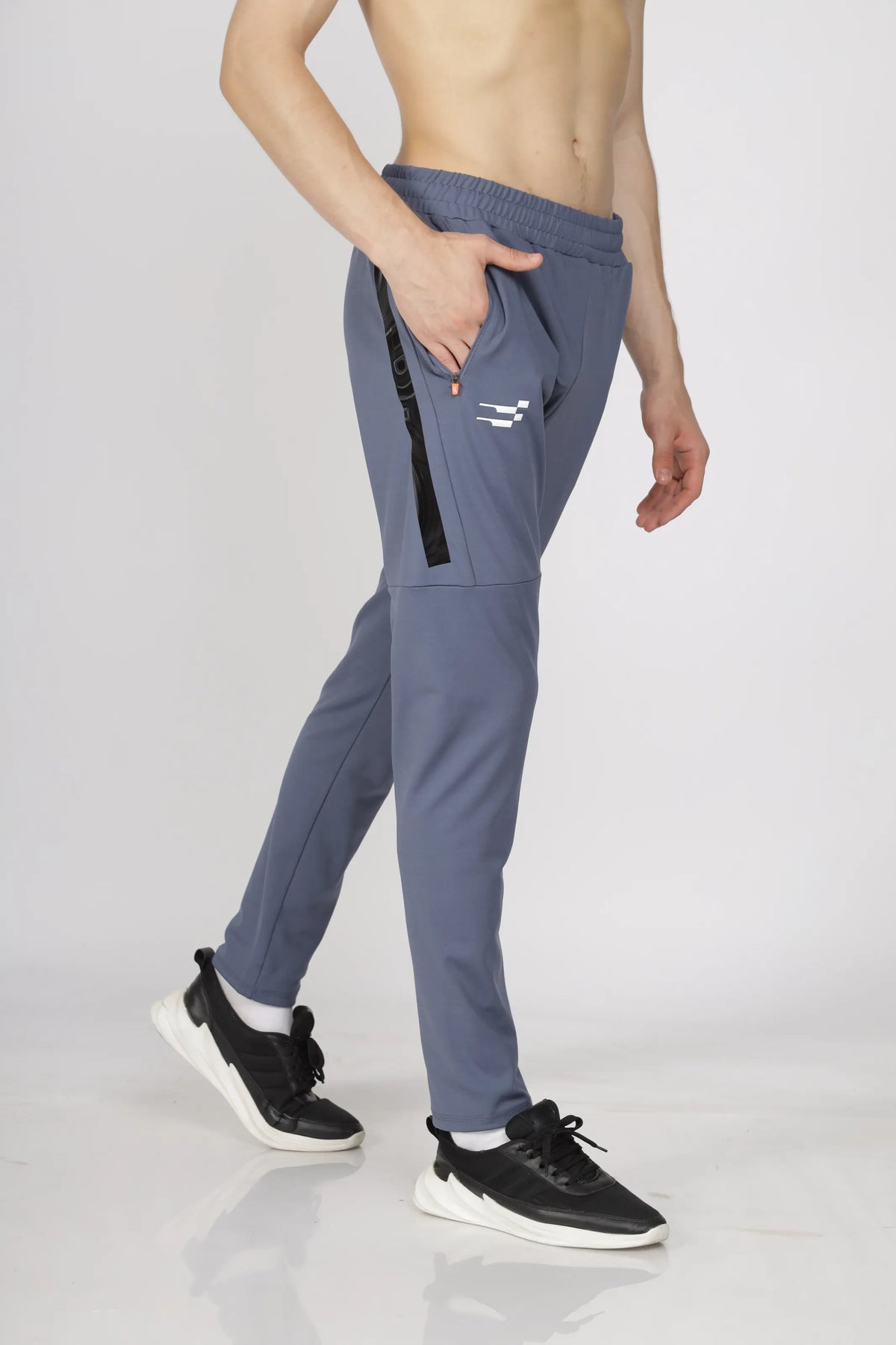 Max-Out Training Track Pant in grey, three-quarter view with a hand in the side pocket