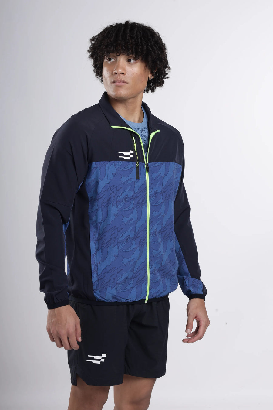 Quantum Performance Track Top in navy, three-quarter view on a model showing the blue camo panel and lime zip