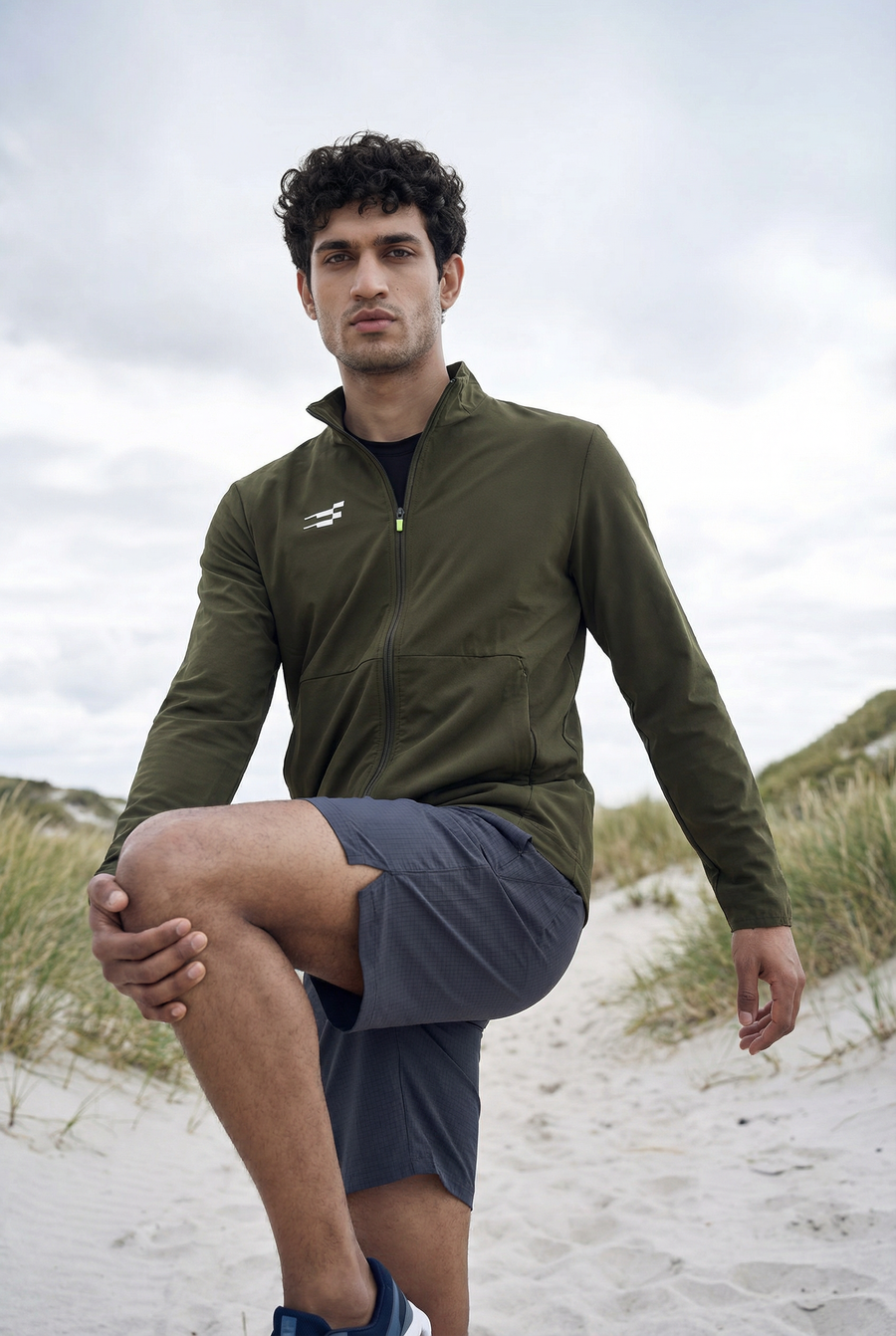 Tech-Shell Performance Track-Top in sage breeze, worn on a sand dune by a model in a zip-up olive green jacket with shorts
